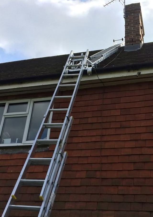 Sweeping work on a roof with ladders in place